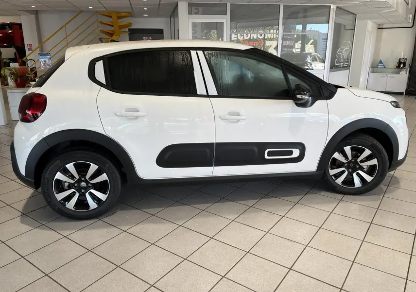 Profil droit d'une Citroën C3 blanche avec Airbump noir et jantes alliage diamantées en showroom.