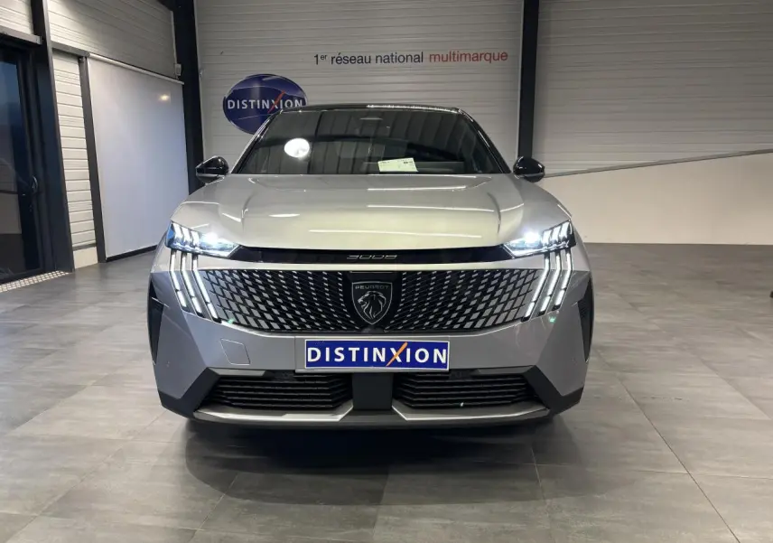 Vue frontale du Peugeot 3008 gris Artense avec calandre noire laquée et feux LED à griffes allumés dans un showroom.