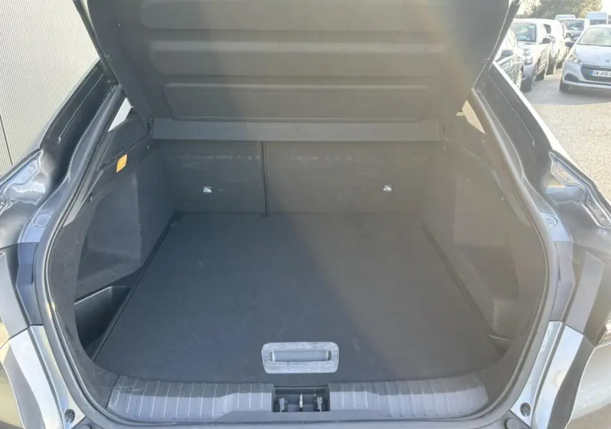 Coffre ouvert vu de l'arrière d'une Renault Arkana gris métallisé, montrant un espace de chargement vide et propre.