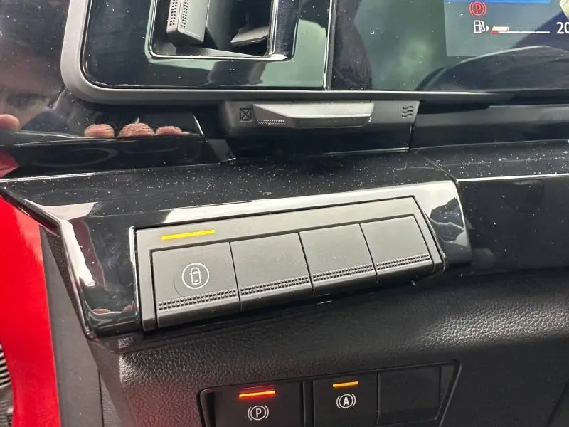 Détail du tableau de bord du Renault Austral 2025 Rouge Flamme, avec boutons de verrouillage et voyants lumineux.