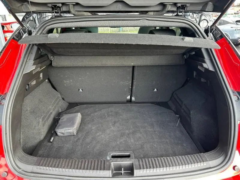 Coffre ouvert vu de l'arrière d'un Renault Austral 2025 Rouge Flamme, montrant l'espace de chargement vide avec cache-bagages relevé.