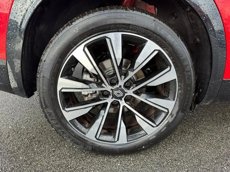 Gros plan sur la roue avant droite avec jante alliage bicolore du Renault Austral Rouge Flamme 2025.