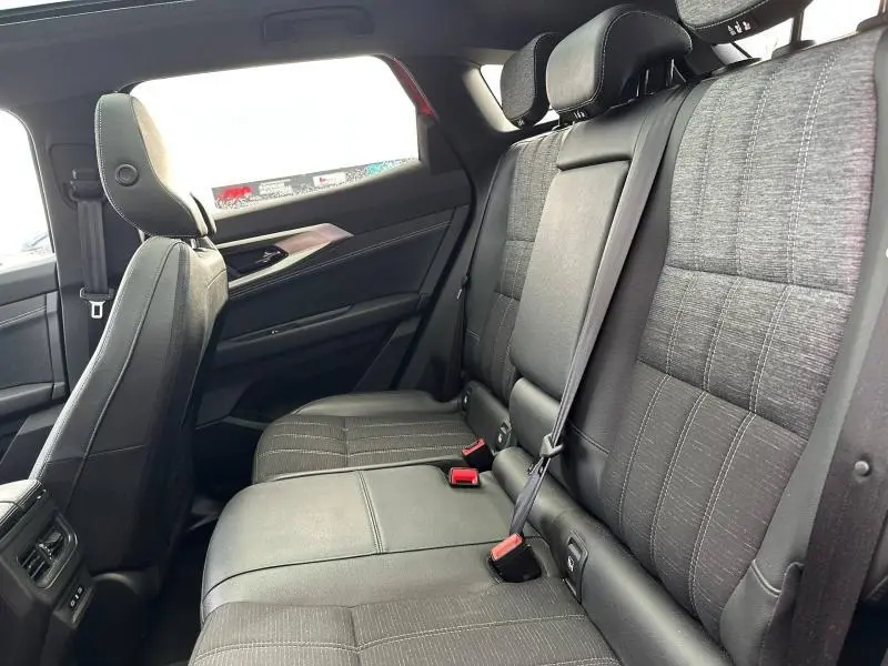 Vue intérieure arrière côté droit du Renault Austral 2025, sièges tissu gris avec ceintures de sécurité visibles.