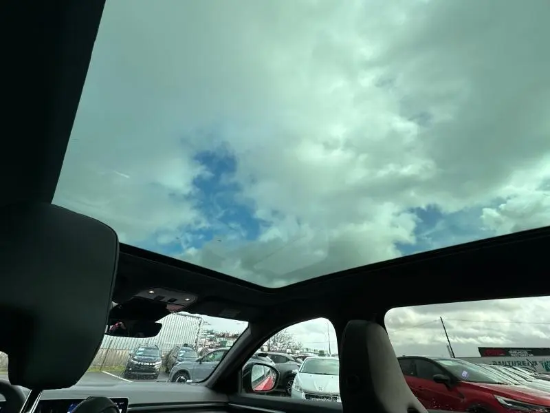 Vue intérieure du toit panoramique du Renault Austral 2025, avec ciel nuageux visible à travers la vitre.