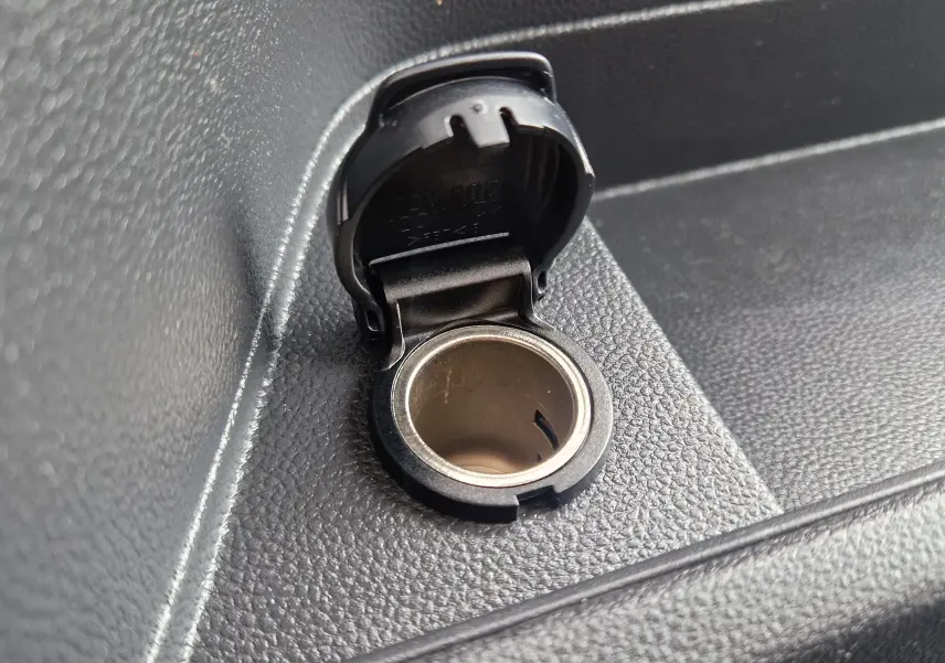Prise allume-cigare noire ouverte sur la console intérieure du Renault Master Châssis Cabine blanc, version benne L2 2024.