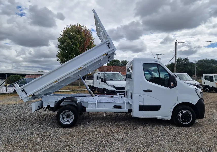 Vue de profil droit du Renault Master Châssis Cabine blanc 2024 avec benne relevée et roues jumelées arrière visibles.