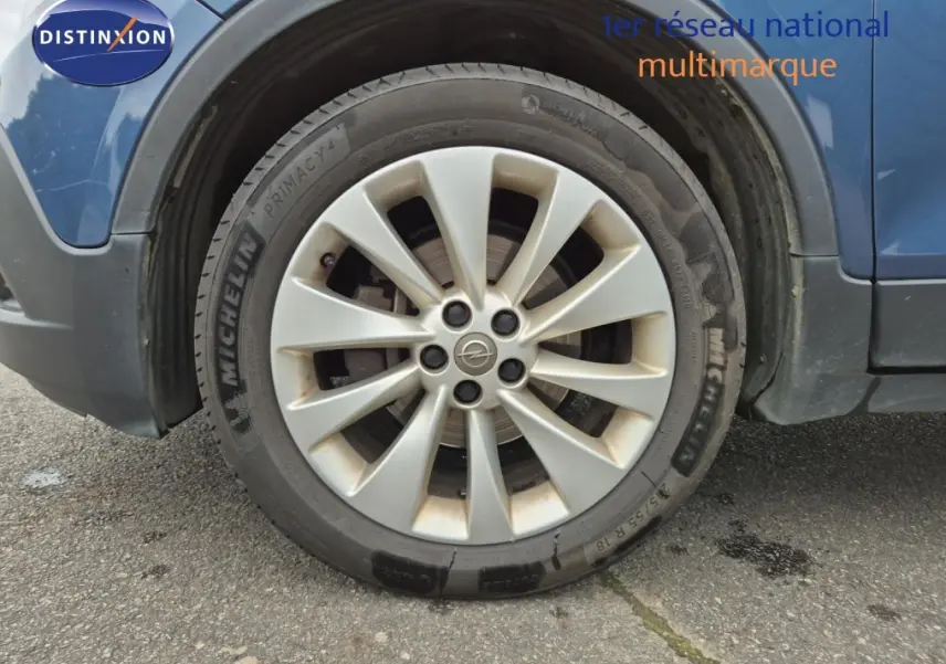 Gros plan sur la roue avant gauche d’un Opel Mokka bleu outremer avec jante alu et pneu Michelin.