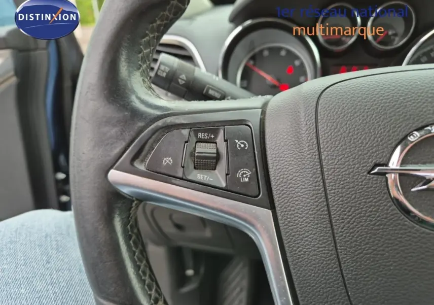 Gros plan sur le volant cuir de l'Opel Mokka 2015, montrant les commandes de régulateur de vitesse côté gauche.