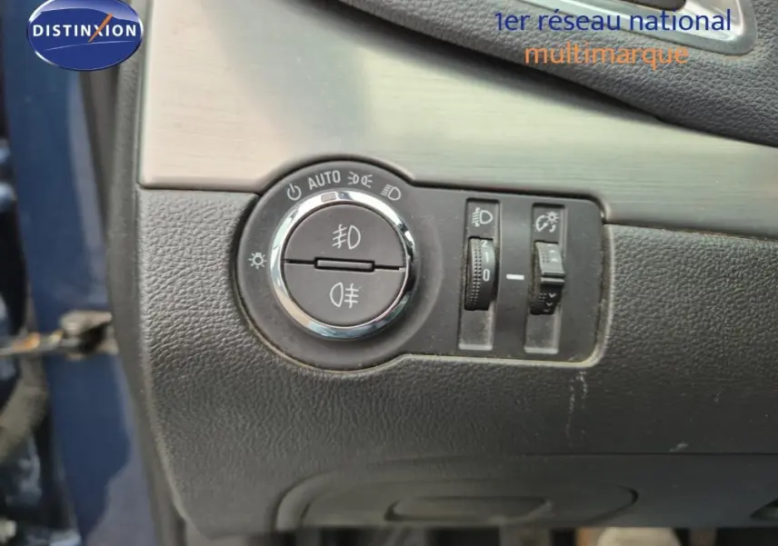 Détail des commandes d’éclairage sur panneau noir intérieur, porte bleu outremer partiellement visible, Opel Mokka 2015.