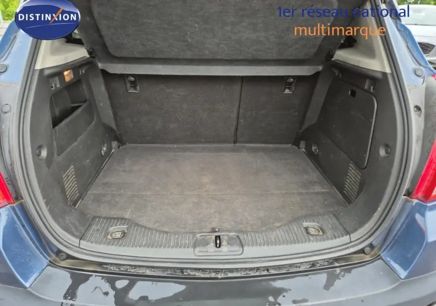 Coffre ouvert d’un Opel Mokka bleu outremer, vue arrière montrant l’espace de chargement vide et les parois intérieures noires.