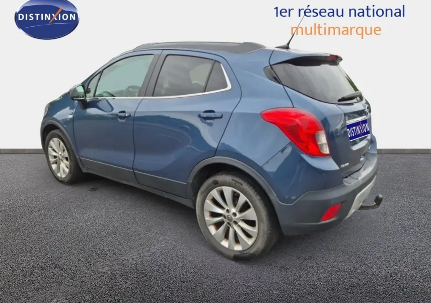 Opel Mokka bleu outremer vu de trois quarts arrière droit, avec barres de toit et jantes alu visibles.