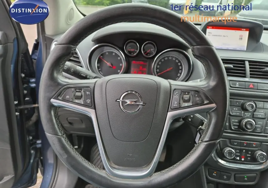 Vue intérieure centrée sur le volant cuir Opel Mokka bleu outremer, avec tableau de bord et console centrale visibles.