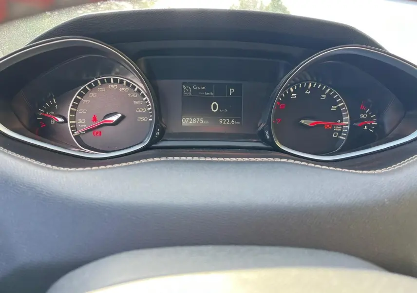 Tableau de bord de Peugeot 308 SW gris clair, affichage numérique central et compteurs analogiques éclairés.