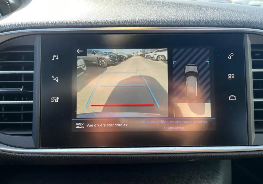 Écran tactile du tableau de bord montrant la caméra de recul et l'aide au stationnement du Peugeot 308 SW gris clair.