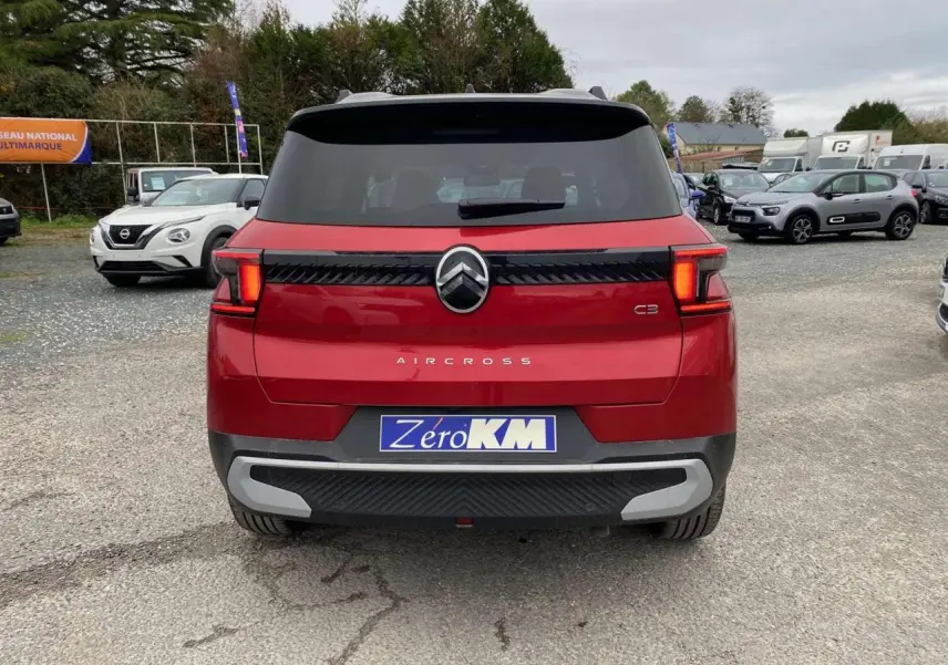 Vue arrière d'un Citroën C3 Aircross rouge Elixir avec toit noir et feux arrière LED 3D allumés.