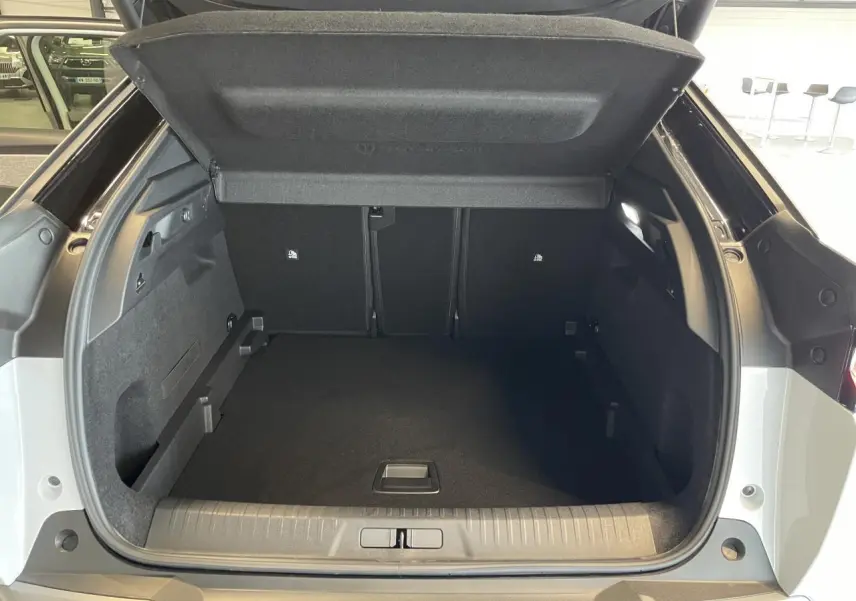Coffre ouvert vu de l'arrière d'un Peugeot 3008 blanc Okenite avec intérieur noir et habillage soigné.