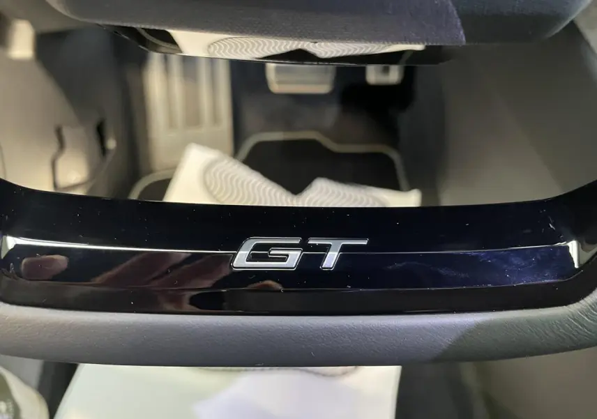 Gros plan sur le badge GT noir laqué sur la console centrale du Peugeot 3008 blanc Okenite.