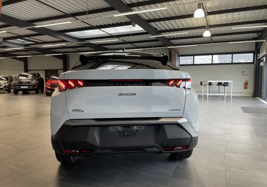 Vue arrière d'un Peugeot 3008 blanc Okenite hybride 2025 avec feux arrière à griffes LED et bandeau noir laqué.