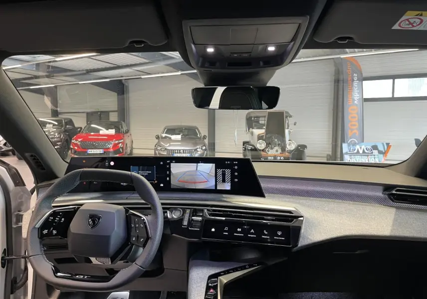 Vue intérieure avant du Peugeot 3008 GT 2025, tableau de bord avec écran panoramique et volant compact noir.