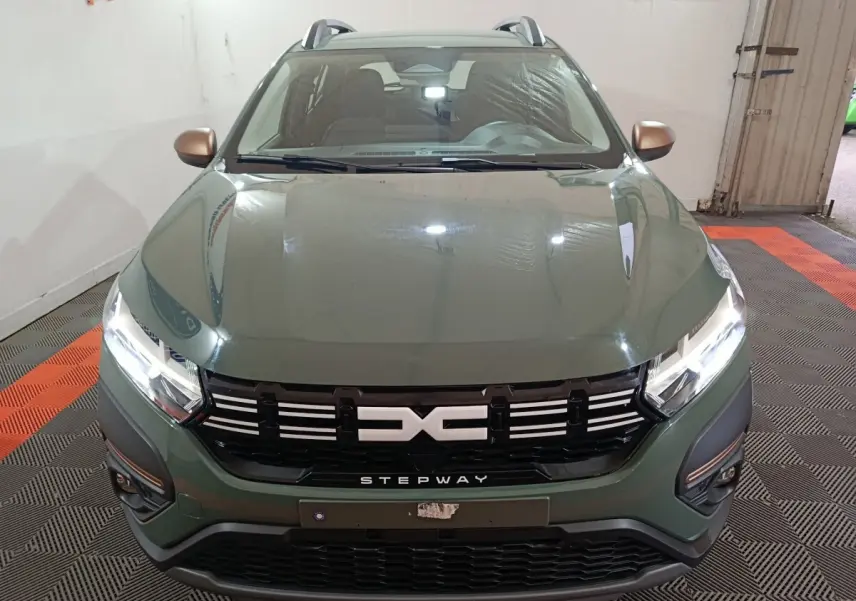 Vue avant rapprochée d'une Dacia Sandero Extreme+ TCe 110 2024 vert avec calandre noire et rétroviseurs cuivrés.