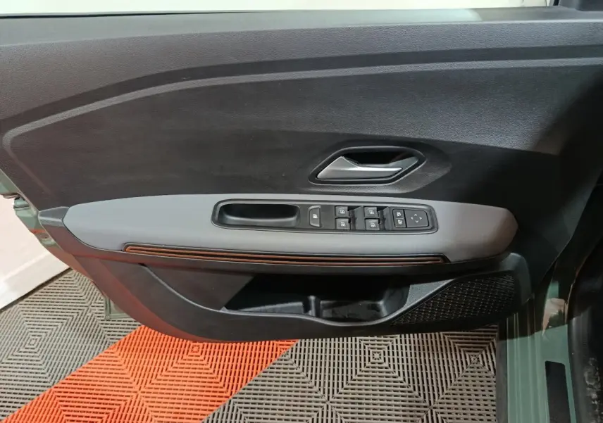 Vue rapprochée de la porte avant gauche de la Dacia Sandero Extreme+ 2024, avec commandes électriques et garniture grise.