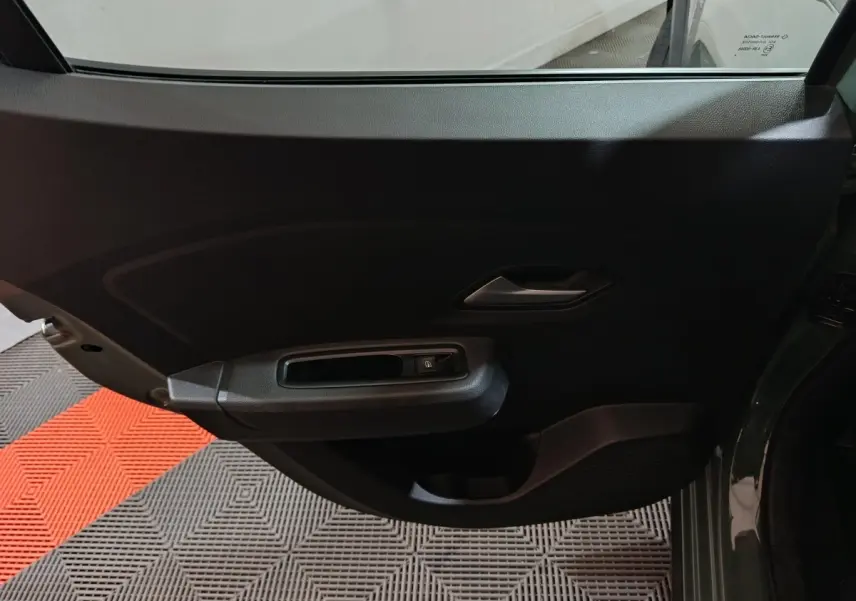 Vue intérieure de la porte arrière gauche de la Dacia Sandero Extreme+ TCe 110 2024 en vert, avec poignée et commande de vitre.