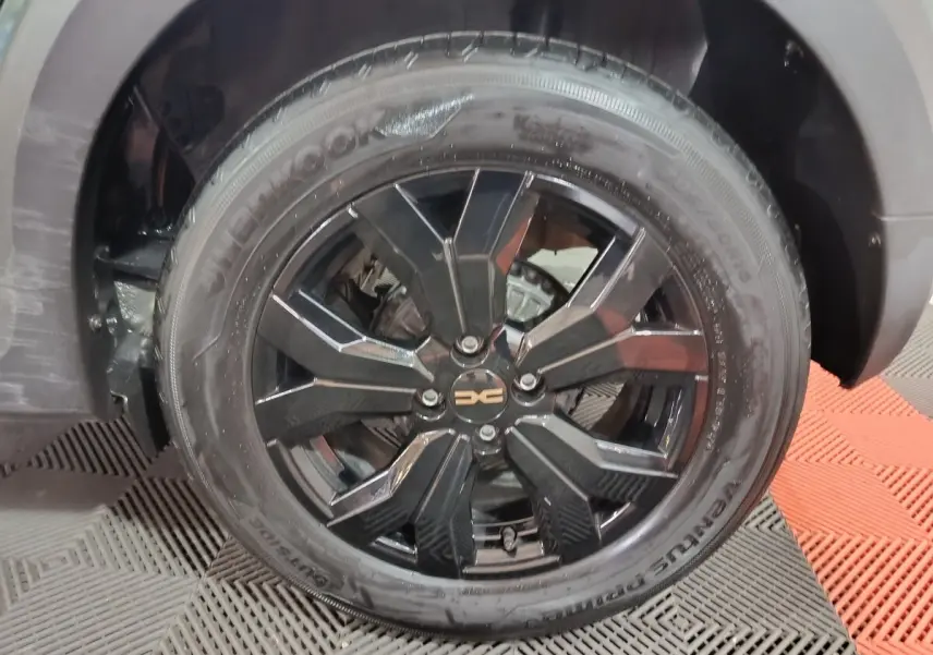 Gros plan sur la roue avant droite noire brillante de la Dacia Sandero Extreme+ TCe 110 verte de 2024.