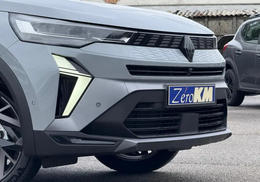 Vue avant droite du Renault Symbioz gris Rafale, mettant en valeur ses phares LED en forme de flèche et sa calandre moderne.