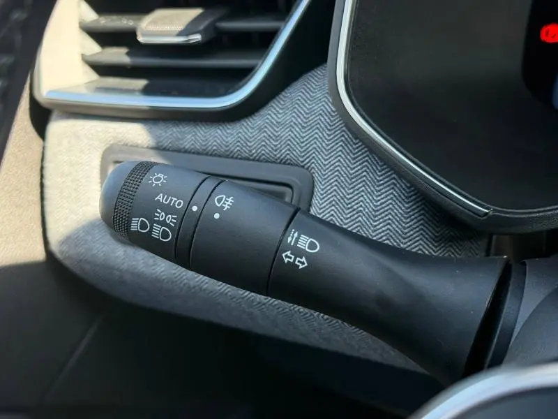 Gros plan sur la commande des feux et clignotants dans l'habitacle du Renault Clio 2025, avec garniture grise à chevrons.