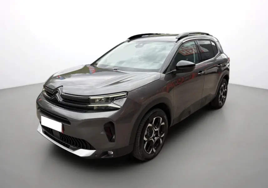 Citroën C5 Aircross gris platinium en 3/4 avant droit, avec jantes alu 18 pouces et barres de toit visibles.