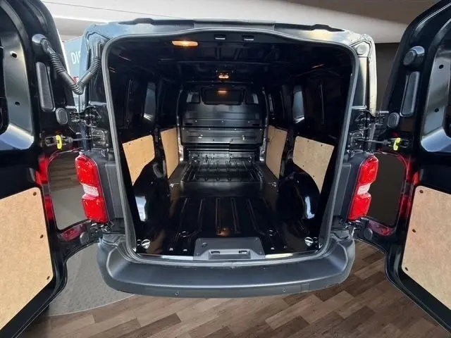 Vue arrière ouverte du Citroën Jumpy noir 2026, montrant l'espace de chargement vide avec parois protégées en bois clair.