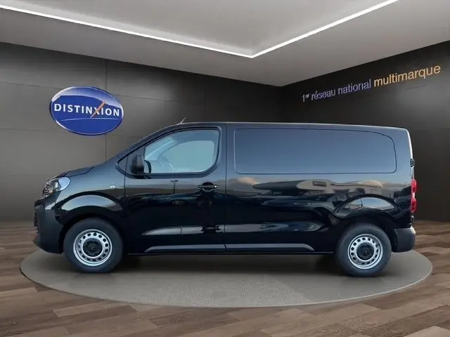 Vue latérale droite d’un utilitaire Citroën Jumpy noir, sans vitres latérales arrière, sur fond intérieur showroom.