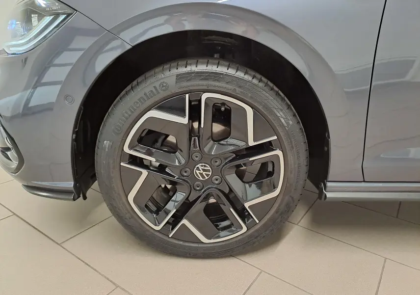 Gros plan sur la roue avant gauche d'une Volkswagen Polo 2025 gris cendré avec jante alliage R-Line noire et argent.