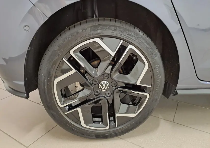 Gros plan sur la roue avant droite d’une Volkswagen Polo gris cendré avec jante alliage noire et argentée.
