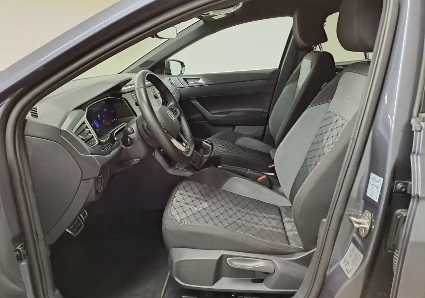 Vue intérieure côté conducteur d'une Volkswagen Polo gris cendré 2025, sièges tissu avec surpiqûres et volant multifonction.