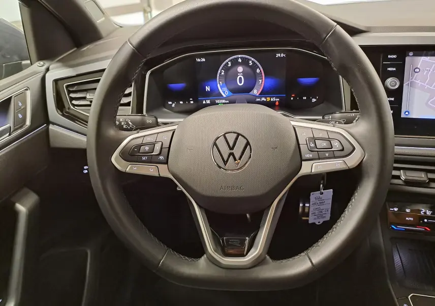 Vue intérieure centrée sur le volant multifonction d'une Volkswagen Polo 2025, avec tableau de bord numérique et écran tactile.