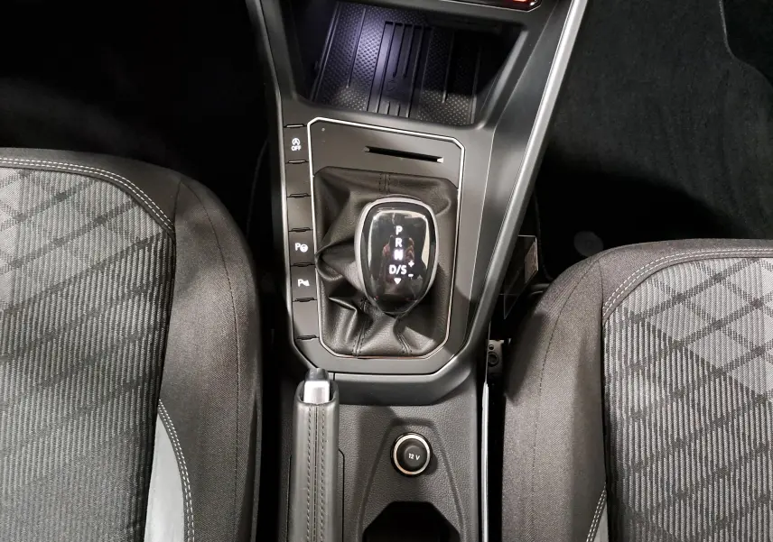 Vue plongeante sur la console centrale de la Volkswagen Polo 1.0 TSI 116 DSG7 R-Line Edition avec levier de vitesse automatique et sièges tissu gris.