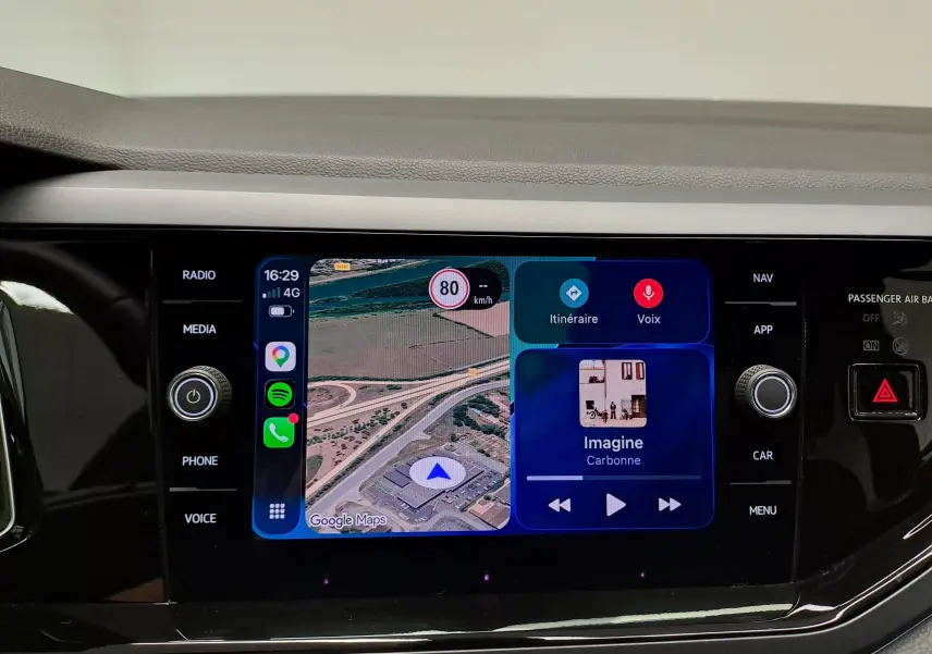 Écran tactile central du Volkswagen Polo 2025 affichant la navigation et la musique, entouré de commandes noires brillantes.