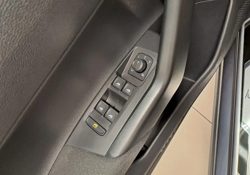 Détail des commandes de lève-vitres et réglage des rétroviseurs côté conducteur d'une Volkswagen Polo gris cendré 2025.