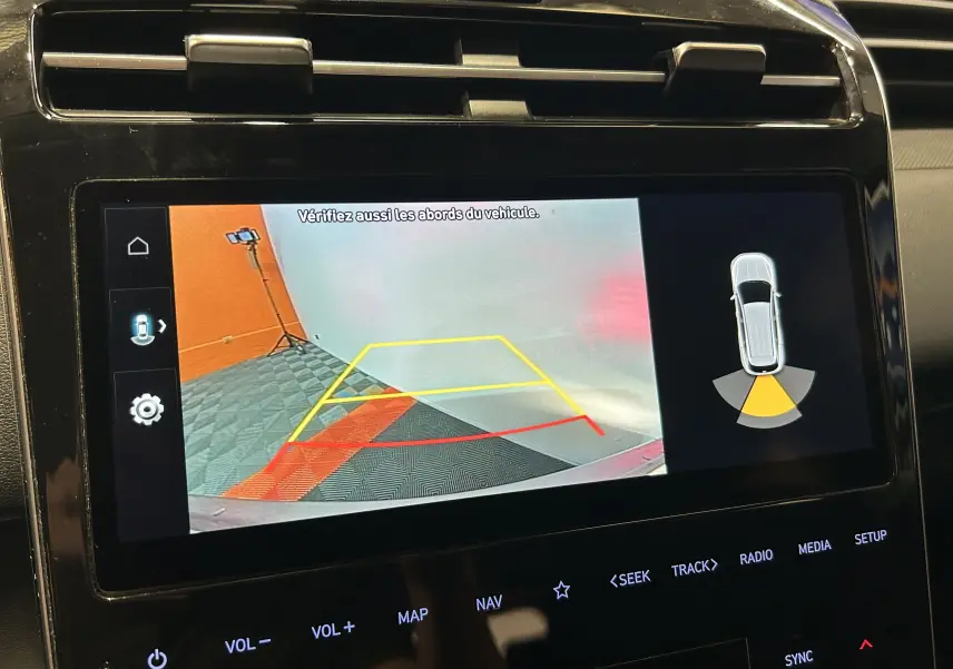 Écran de caméra de recul du Hyundai Tucson Hybrid 2022 affichant les lignes de guidage et l'alerte de proximité arrière.