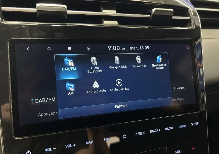 Écran tactile central du Hyundai Tucson Hybrid 2022 affichant les options multimédia, dans un intérieur noir.
