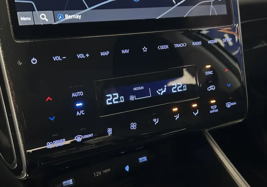 Détail de la console centrale noire brillante du Hyundai Tucson Hybrid 2022 avec écran tactile et commandes climatisation digitales.