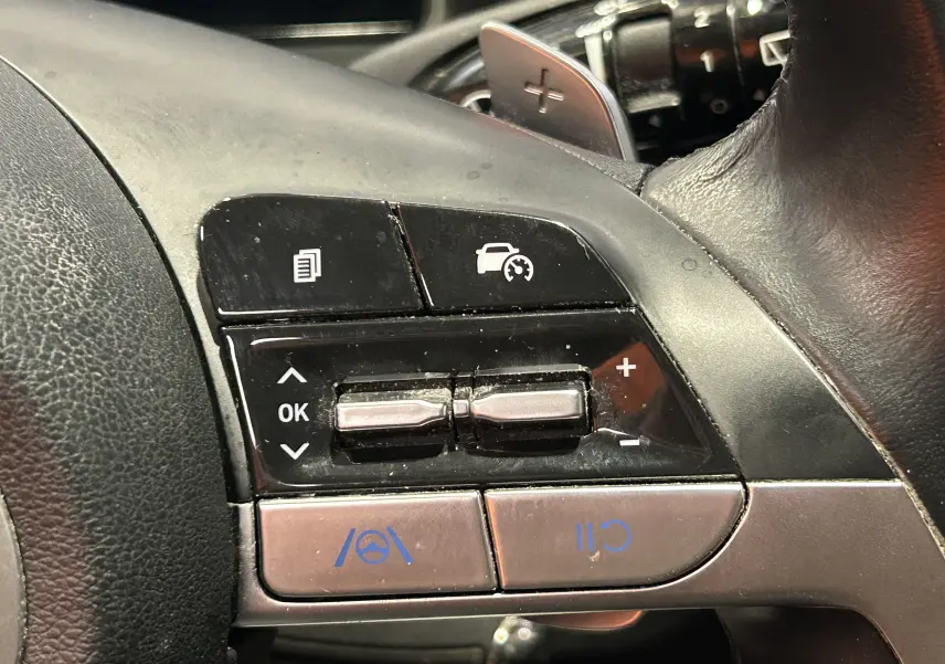 Gros plan sur les commandes de régulateur de vitesse au volant noir du Hyundai Tucson Hybrid 2022.