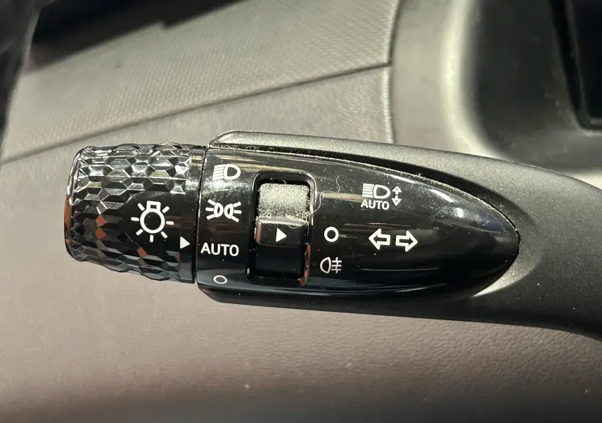 Gros plan sur la commande des phares et clignotants noire avec motifs texturés dans l'habitacle du Hyundai Tucson gris.