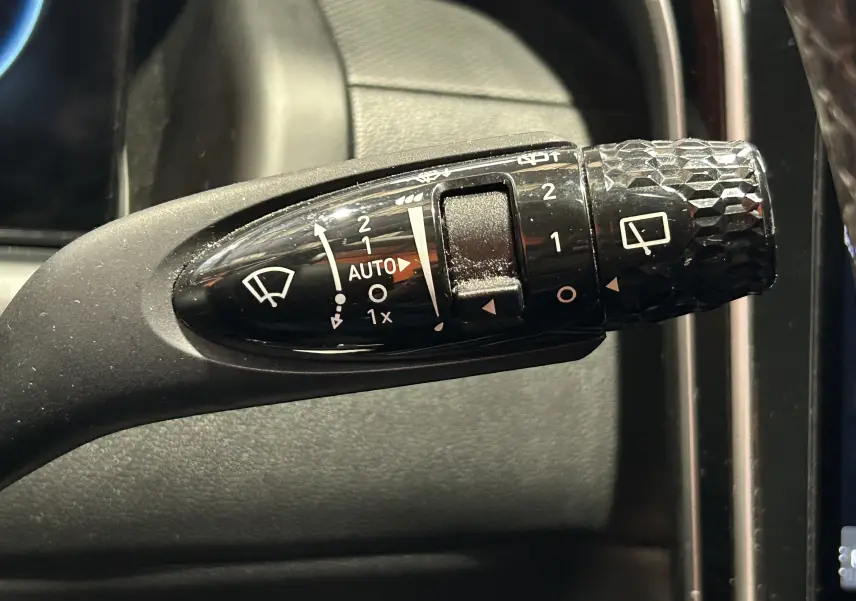 Gros plan sur la commande de l’essuie-glace noir à motifs hexagonaux dans l’habitacle d’un Hyundai Tucson gris.