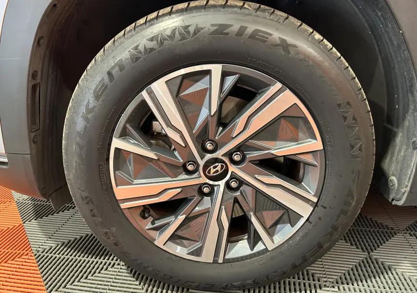 Gros plan sur la roue avant gauche du Hyundai Tucson gris avec jante alliage au design géométrique distinctif.