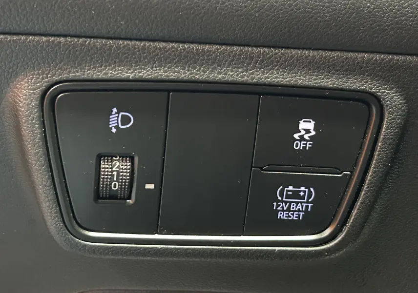Gros plan sur les commandes intérieures du Hyundai Tucson Hybrid 2022, avec réglage des phares et bouton de désactivation de l'ESP.