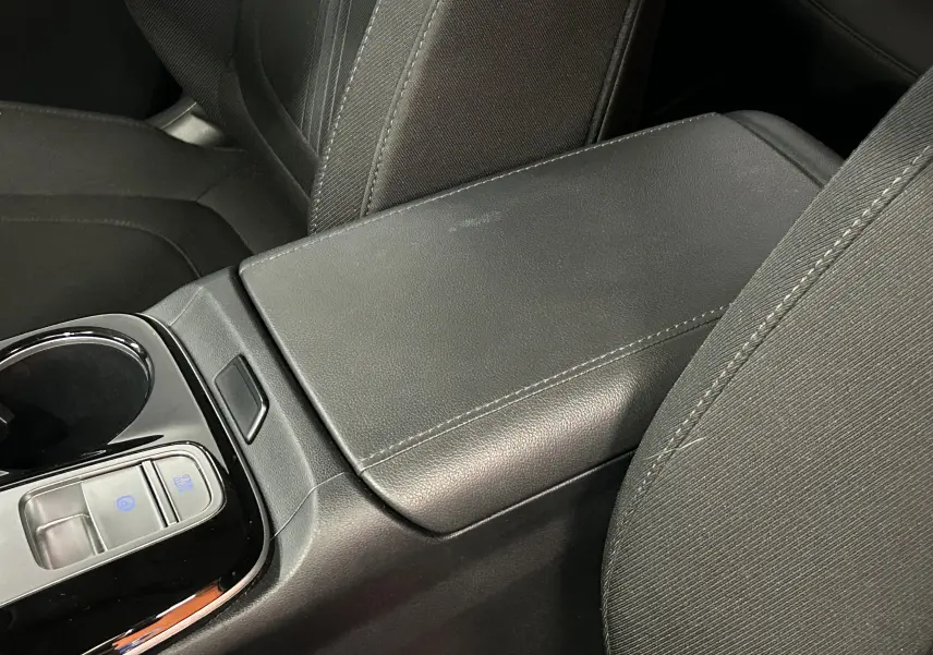 Détail de l'accoudoir central noir en cuir et tissu avec commandes électroniques dans l'habitacle du Hyundai Tucson hybride 2022.