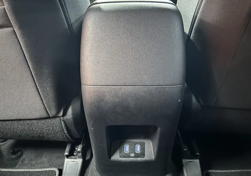 Vue rapprochée de la console centrale arrière noire du Hyundai Tucson Hybrid avec deux ports USB visibles en bas.
