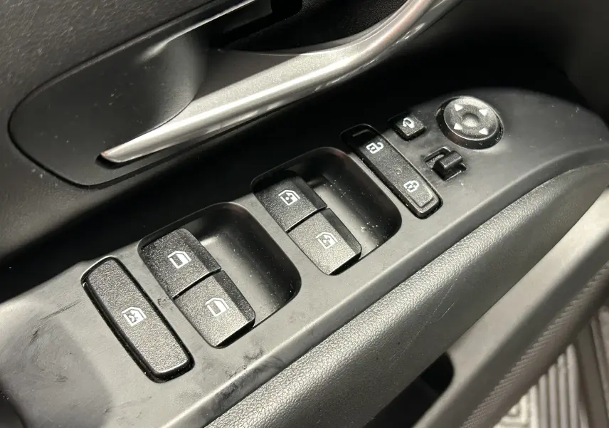 Gros plan sur les commandes de lève-vitres et rétroviseurs côté conducteur d’un Hyundai Tucson gris, intérieur noir.